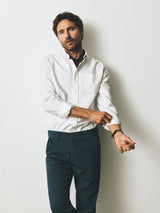 A man wearing a white button-down shirt and Blue de Gênes BGpaulo Pavia V3 Chino - Orion Blue rolls up his sleeves.