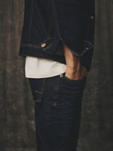 Side view of a person wearing BGvinci Pala Dark V3 Jeans and a matching denim jacket over a white shirt, with a hand in the pocket of the regular fit jeans.