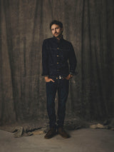 A man wearing a dark denim jacket and BGvinci Pala Dark V3 Jeans - Dark Blue Denim standing against a gray backdrop.