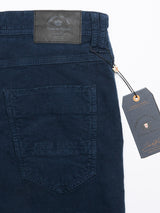 A close-up of the Paulo Tucan Chino in navy by Blue de Gênes highlights the back pocket, brand label, and tag. The corduroy fabric features a textured ribbed pattern; the tag hangs from the waistband, proudly displaying Made in Italy with a logo and text.
