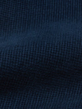 A close-up of the Paulo Tucan Chino in Navy by Blue de Gênes showcases a deep blue fabric with a textured, waffle-like pattern. Its gentle waves and shadows embody elegant Made in Italy craftsmanship.