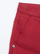A close-up of Blue de Gênes Teo Milano Shorts in vibrant Havana Red reveals a side pocket and subtle cross-emblem metal detail, crafted from a cotton/linen blend. The shorts feature visible stitching and textured fabric for enhanced style and comfort.