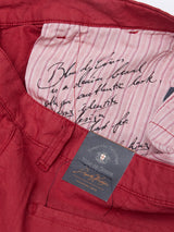 Close-up of Havana Red Teo Milano Shorts with a striped inner lining featuring cursive handwriting. A black tag showcases the Blue de Gênes logo, while the detailed stitching and cotton/linen blend texture are beautifully highlighted.