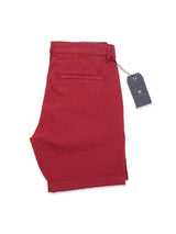 Havana Red Teo Milano Shorts by Blue de Gênes are neatly folded with a navy tag tied to the belt loop. Made from a cotton/linen blend, these shorts feature a back pocket with an embroidered logo and Teo branding details on the plain white tag.