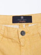 Close-up of yellow Teo Milano Shorts in Sand by Blue de Gênes, featuring a button and label, ornate stitching at the waistband, and crafted from a comfortable cotton/linen blend for a stylish fit.