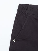 Close-up of Teo Milano Shorts - Jet Black by Blue de Gênes, featuring a right-side pocket. The cotton/linen blend fabric has a textured look, and theres a small black and white checkered decorative tag near the pocket.