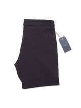 Jet black Teo Milano Shorts are crafted from a comfortable cotton/linen blend with a back pocket featuring an embroidered logo. A blue tag with string shows the Blue de Gênes brand and information. The shorts are folded neatly on a white background.
