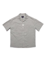 The Blue de Gênes Colonnello Delo shirt features a short-sleeved button-up design with a black and white jacquard geometric circular pattern, classic collar, and is laid flat, facing up.