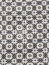 The Colonnello Delo shirt by Blue de Gênes features a textured cotton jacquard pattern in dark brown and navy on a light background, highlighted by a central circular stitched patch that suggests elegant repair or embellishment.