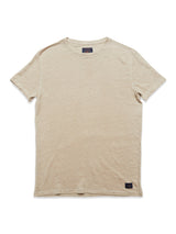A Totti T-Shirt - Pebble Beige by Blue de Gênes is shown flat on a white background. Made from 100% linen jersey, it has short sleeves, a round neckline, and features a small dark tag at the lower left side highlighting its natural texture.