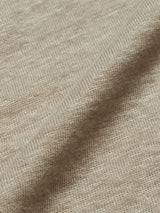 Close-up of the Totti T-Shirt in Pebble Beige by Blue de Gênes shows a natural texture with visible stitches forming a uniform pattern. The craftsmanship of this 100% Linen Jersey is highlighted by a subtle diagonal fold, echoing that of a Linen Crewneck T-Shirt.