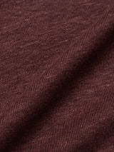 Close-up of the Totti T-Shirt - Prune by Blue de Gênes, featuring a textured dark brown fabric that resembles 100% Linen Jersey. The fabric is slightly folded, emphasizing its natural texture and subtle color variations.