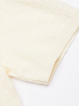 A close-up of the Primo Polo Knit - Ecru by Blue de Gênes shows its soft, cream-colored fabric with subtle stitching details and a smooth finish. The knit, perfect for summer, lies against a white surface.