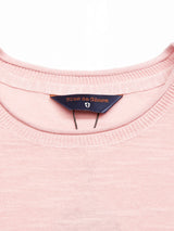 Close-up of the Monte Knit - Porcelain Pink jumper by Blue de Gênes, featuring a ribbed crewneck. The navy blue tag embossed in orange includes a small anchor graphic. Crafted from a cotton/linen blend.