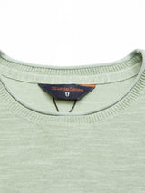 Close-up of the Monte Knit - Green Bay, a light green sweater with a ribbed neckline and roll-rib hem, crafted from a cozy cotton/linen blend. A dark Blue de Gênes label is sewn inside the collar.