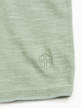 Close-up of Blue de Gênes Monte Knit - Green Bay, featuring light green textured fabric made from a cotton/linen blend with an embroidered shield emblem and a roll-rib hem.
