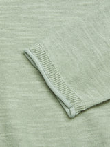 Close-up of Blue de Gênes Monte Knit - Green Bay fabric showcasing a light green color with a folded roll-rib hem. It features soft texture and visible stitching, creating a subtle pattern reminiscent of a cozy crewneck jumper crafted from a cotton/linen blend.