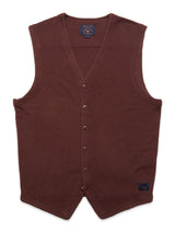 The Zorba Knit Waistcoat by Blue de Gênes is a sleeveless, prune-colored V-neck design featuring six Corozo nut buttons and a small logo patch near the bottom hem, shown laid flat against a white background.