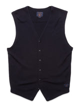 The Zorba Knit Waistcoat in navy by Blue de GĂȘnes is a sleeveless knit design featuring a V-neckline with six corozo nut buttons and a small fabric label near the hem, set against a plain white backdrop.