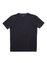 The Nipote AW S/S Grandad T-shirt in Dark Navy by Blue de Gênes is a collarless, short-sleeve design with a round neckline and three-button placket. Crafted from cotton interlock jersey, its laid flat on a white background to emphasize its minimalist style and stitch details.