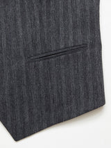 The Canna Dori Gilet - Grey Stripe from Blue de Gênes showcases Portuguese tailoring with a close-up of its gray pinstriped fabric, neatly sewn horizontal pocket, and detailed stitching for a classic formal look.