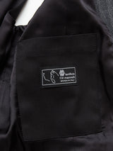 Close-up of a black fabric inside a garment from Blue de Gênes, displaying a label with white stitching that reads, Lanificio F.lli Mannelli WOVEN IN ITALY, featuring a mountain range logo—crafted from an exquisite Italian cotton-wool blend for the Canna Dori Gilet - Grey stripe.