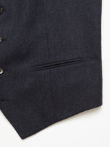 Close-up of a navy fabric with a fine texture, part of the Canna Santo Gilet by Blue de Gênes. It features an Italian wool blend with a vertical seam, concealed slit pocket, and four black buttons on the left side, exuding exquisite Portuguese tailoring.