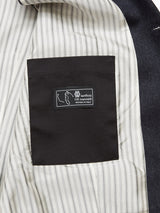 The image reveals the interior of a Canna Santo Gilet - Navy by Blue de Gênes, featuring black and white vertical stripes. A black pocket with a label reads lanificio f.lli cerruti dal 1881 Woven in Italy, emphasizing its luxurious Italian wool craftsmanship.