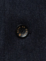 Close-up of a navy button on an Italian wool blend fabric from the Canna Santo Gilet - Navy by Blue de Gênes, inscribed with Blue de Gênes and a small emblem beneath, highlighting exquisite Portuguese tailoring.