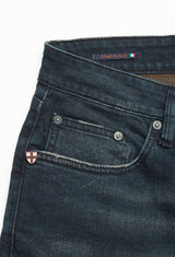 Close-up of Vinci Haworth Jeans - Denim Blue by Blue de Gênes, crafted from Comfort Stretch Denim, featuring a small front pocket with rivets. An Italian flag tag indicates Made in Italy, and a shield emblem with a red cross on white adorns the area near the pocket.