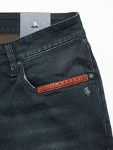 Close-up of Blue de Gênes Vinci Haworth Jeans in denim blue with leather pocket detail. Worn texture and handmade retouching near the pocket enhance their look. Waistband and inner lining feature comfort stretch denim.