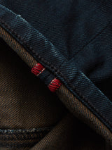 Close-up of folded Vinci Haworth Jeans - Denim Blue from Blue de Gênes, revealing a hem with red stitching. The texture and handmade retouching details highlight the contrast between the blue denim and red thread accents.