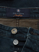 Close-up of Repi Haworth Used Jeans by Blue de Gênes, showing the label and metal buttons. The comfort stretch denim has a textured look with visible stitching, offering a regular slim fit.