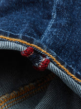 A close-up of Blue de Gênes Repi Scan Used Jeans in mid blue denim highlights the textured weave, orange stitching, and red thread accents on the hem, epitomizing comfort stretch denim.
