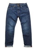 The Giacomo 77 Dark Used Jeans by Blue de Gênes, in mid blue denim, feature rigid construction with slight fading and distressing. These jeans offer a relaxed loose-fit style, classic five-pocket design, rolled-up cuffs, and belt loops.