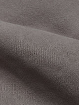 Close-up of a folded piece of Blue de Gênes Paco Papago Chino in Stormy Grey, showcasing its smooth texture and refined style with a fine weave. The chinos appear soft and slightly reflective under the light.