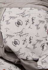 The Paco Papago Chino by Blue de Gênes features a fabric with cartoon mouse sketches, anchors, and phrases on a light gray background. This garment-dyed piece in Stormy Grey exudes refined style with visible stitching and seams, reminiscent of Moleskin chinos.