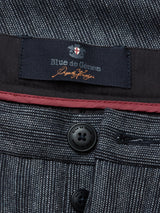 Close-up of the Panco Dori Chinos waistband reveals a Blue de Gênes label and Made in Italy text on dark fabric, with red trim and buttons engraved with Blue de Gênes. The Italian cotton-wool blend fabric features an irregular pinstripe pattern.