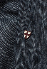 A small, shield-shaped pin with a red and white cross design is attached to the textured fabric of Blue de Gênes Panco Dori Chino - Grey stripe. The pin contrasts with the irregular pinstripe pattern of this Italian cotton-wool blend material.