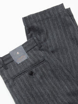 The Panco Dori Chino by Blue de Gênes features a sophisticated irregular pinstripe, crafted from an Italian cotton-wool blend in gray. It includes a folded waistband and belt loops, a buttoned back pocket, and a black tag with the brand logo.