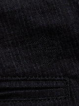 Close-up of Blue de Gênes Menzo Alvaro Chino in navy denim, featuring a subtle embroidered shield pattern and visible stitching at seams and pockets. The classic, stylish material includes a comfort stretch for versatility.