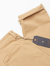 Close-up of a pair of Blue de Gênes Menzo Dobby Chino - Khaki pants with a folded waistband and back pocket. These chinos feature comfort stretch for flexibility, with a dark tag and decorative logo in red and white, adding a vintage touch.