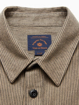 Close-up of the Ginotto Oregon Shirt - Pebble Beige collar reveals a blue and orange Blue de Gênes label. The classic fit of this beige and black yarn-dye striped shirt is highlighted, featuring a brushed cotton texture with one visible black button.