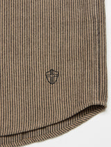 The Ginotto Oregon Shirt - Pebble Beige by Blue de Gênes showcases a brushed cotton fabric with vertical beige and black yarn-dye stripes, featuring a black embroidered shield emblem near the edge. It has a classic fit and is finished with a rounded hem.