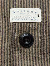 Close-up of the Ginotto Oregon Shirt - Pebble Beige by Blue de Gênes, featuring brown and black yarn-dye stripes, a black button, and a classic fit design with a tag above stating: Buttons made of real natural corozo nut.