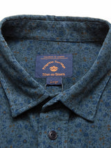 Close-up of the Enrico Cord Shirt - Blue Pattern, crafted in soft baby corduroy with brown dots. The brand label inside reads Blue de Gênes, Large. Its neatly folded collar adds a touch of elegance.