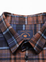 The Zamboni Quadro Shirt by Blue de Gênes features a close-up of its navy check pattern in brown, blue, and black. Made from a winter cotton-linen blend, it includes a button-down collar with visible buttons. The inside tag reads Progetto Heritage and Blue de Gênes.
