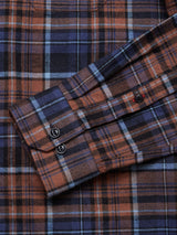 A close-up of the Zamboni Quadro Shirt - Navy Check by Blue de Gênes showcases its winter cotton-linen blend with brown, blue, and black yarn-dye checks. The long sleeve is elegantly folded over, revealing two black cuff buttons. The fabric looks soft and warm.