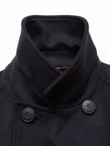 Close-up of Blue de Gênes Peacoat - Dark Navy, made from textured Melton wool, showcasing a high collar and double-breasted style. It features branded buffalo horn buttons, two visible near the neatly folded collar.