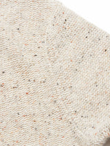 Close-up of the Adamo Knit - Pebble Beige by Blue de Gênes, featuring a speckled pattern with black and orange dots. Crafted from mélange yarn, its weave creates a textured look, highlighting the fabric’s cozy and soft quality.